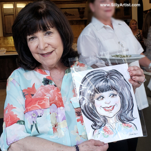 woman holding a caricature at a birthday party in Austin silly artist